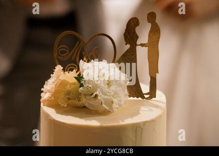 Elegante torta nuziale con decorazioni floreali e silhouette di coppia. Foto Stock