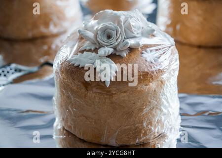 Torta decorata in modo elegante avvolta in plastica con fiori fondente bianchi. Foto Stock