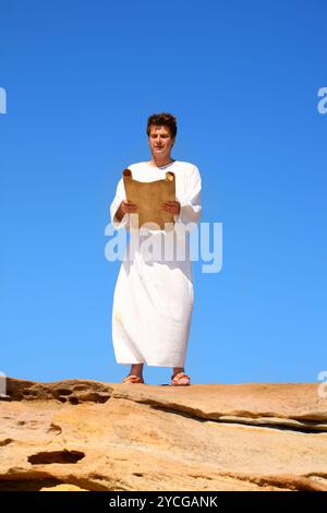 Uomo che legge il rotolo nel paesaggio roccioso del deserto Foto Stock