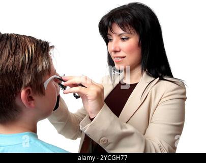 Un optometrista mette i telai di prova su un paziente Foto Stock