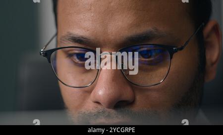 Primo piano occhi maschili concentrati concentrati negli occhiali che guardano lo schermo del monitor del notebook riflesso della luce negli occhiali uomo d'affari di notte Foto Stock