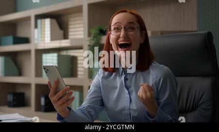 Felice eccitato vincitore femminile donna caucasica business manager lavoratrice d'ufficio donna d'affari riceve un premio di successo per le buone notizie Foto Stock