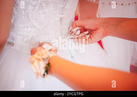 Un bel momento di preparazione nuziale con allacciatura delicata per abiti. Foto Stock