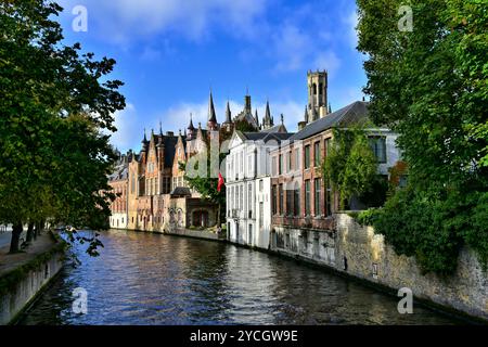 Edifici medievali in mattoni che costeggiano il canale Gronerei, torri del municipio di Bruges del XIV secolo e il campanile in una giornata di sole in autunno a Bruges, Belgio Foto Stock