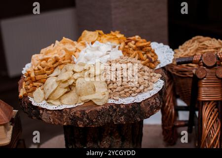 Squisita gamma di spuntini croccanti esposti elegantemente su un piatto di legno rustico. Foto Stock