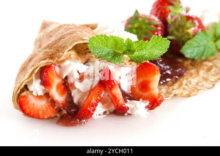 Pancake arrotolati con fragole, panna dolce e menta Foto Stock