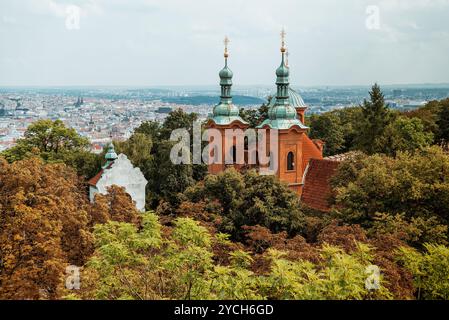 La chiesa di San Lorenzo si innalza sopra il fogliame autunnale con la città di Praga sullo sfondo Foto Stock