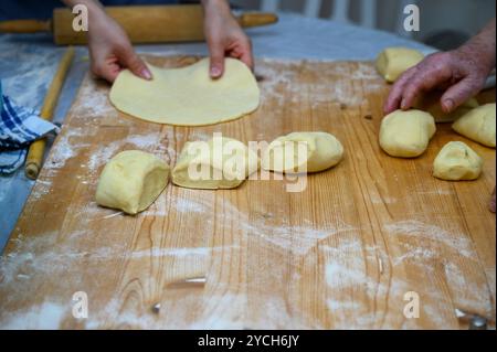 Mani che preparano l'impasto su una superficie di legno infarinata per la cottura Foto Stock