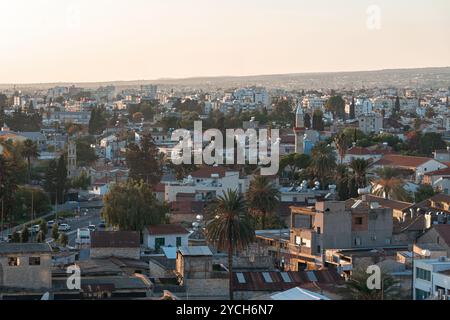 Le palme e i minareti si stagliano contro la luce calda del sole che tramonta in questo paesaggio urbano panoramico Foto Stock