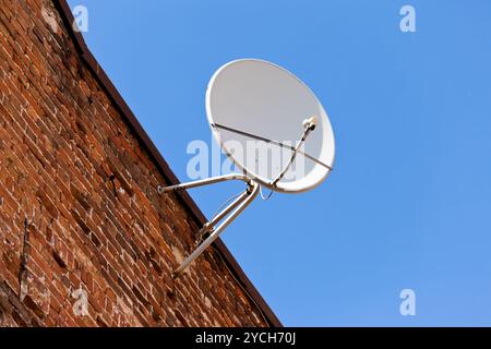 Parabola satellitare montato sul vecchio muro in mattoni. Foto Stock