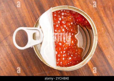 Caviale rosso in banca con cucchiaio su legno Foto Stock