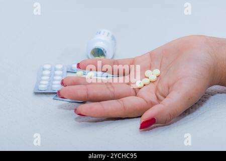 Primo piano della mano di una donna con pillole circondate da un'abbondanza di farmaci; l'assunzione di farmaci senza controllo medico può essere letale. Tema: Foto Stock