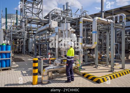 Oberhausen, Nordrhein-Westfalen, Deutschland - Gruener Wasserstoff bei Air liquide, Wasserstoffproduktion im Chemiepark OQ Chemicals. TRAILBLAZER, ein 20 MW-Elektrolyseur zur Herstellung von gruenem, klimaneutralem Wasserstoff. Eine Ingenieurin steht an der Anlage, regelt an einem Schieberventil den Leitungsdurchfluss. Oberhausen Nordrhein-Westfalen Deutschland *** Oberhausen, Renania settentrionale-Vestfalia, Germania idrogeno verde presso Air liquide, produzione di idrogeno presso il parco chimico OQ Chemicals TRAILBLAZER, un elettrolizzatore da 20 MW per la produzione di idrogeno verde e climaticamente neutro un ingegnere sta Foto Stock