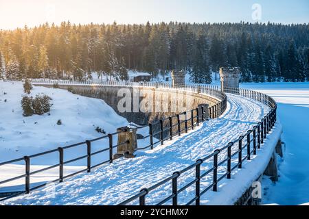 Un tranquillo paesaggio invernale mette in mostra la diga di Cerna Nisa circondata da alberi innevati nelle montagne di Jizera, crogiolandosi alla luce calda del sole in una giornata fresca e limpida. Foto Stock