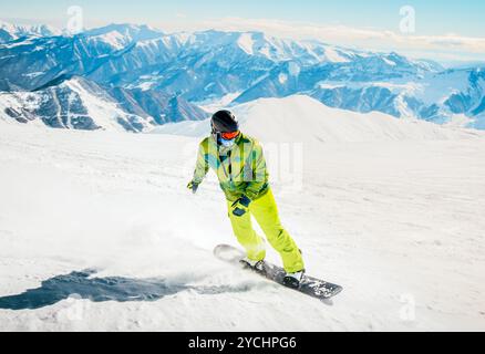 Lo snowboarder si blocca in discesa con lo sfondo delle montagne. Escursioni a cavallo nelle alpi europa destinazioni innevate Foto Stock