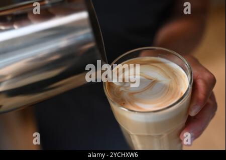 Berlino, Germania. 18 settembre 2024. Una persona versa la schiuma di latte in un bicchiere di caffè. Credito: ELISA Schu/dpa/Alamy Live News Foto Stock