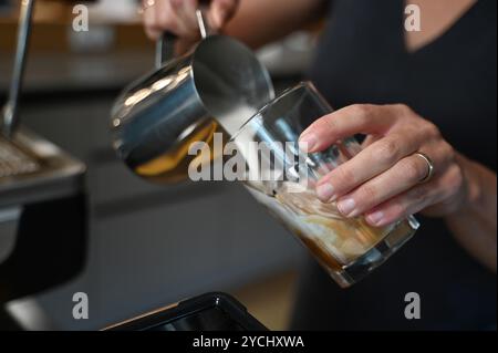 Berlino, Germania. 18 settembre 2024. Una persona versa la schiuma di latte in un bicchiere di caffè. Credito: ELISA Schu/dpa/Alamy Live News Foto Stock