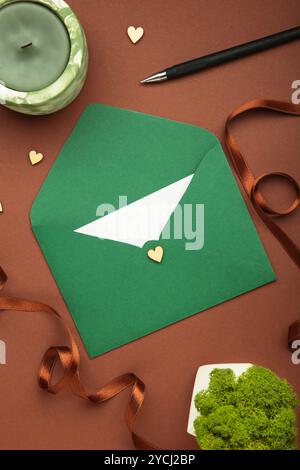 Elegante set di cancelleria per matrimoni. Modelli di biglietti d'invito per matrimoni, busta verde, nastro di seta su sfondo marrone. Foto verticale Foto Stock