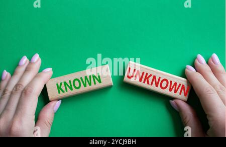 Simbolo noto o sconosciuto. Parola concettuale conosciuta o sconosciuta su blocchi di legno. Mano d'affari. Bellissimo sfondo verde. Azienda e conosciuto o sconosciuto c Foto Stock