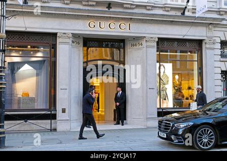 Persone che fanno acquisti che passano davanti a loro e guardano la vetrina del negozio italiano Gucci in Bond Street nell'autunno di ottobre 2024 Londra Inghilterra Regno Unito KATHY DEWITT Foto Stock