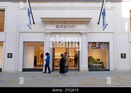 Persone che fanno acquisti che passano davanti a loro e guardano la vetrina del negozio Burberry in ond Street nell'autunno di ottobre 2024 Londra Inghilterra Regno Unito KATHY DEWITT Foto Stock