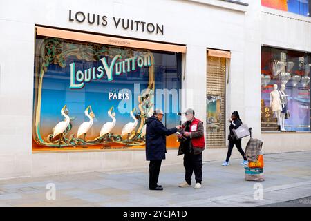 Vista dall'esterno della strada degli acquirenti, vendita di grandi numeri all'esterno della finestra d'ingresso del negozio Louis Vuitton, esterno su Bond Street Londra, Inghilterra, Regno Unito KATHY DEWITT Foto Stock