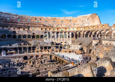 I visitatori si riuniscono all'interno del Colosseo, ammirando l'antica architettura e la storia di questo iconico monumento romano sotto un cielo azzurro. Foto Stock