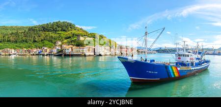 Una barca da pesca che attraversa la baia di Pasajes, di fronte al villaggio di pescatori di San Juan. Gipuzkoa, Paesi Baschi, Spagna. Foto Stock