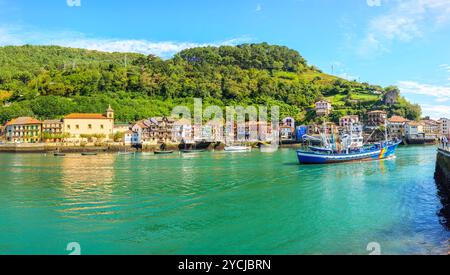 Una barca da pesca che attraversa la baia di Pasajes, di fronte al villaggio di pescatori di San Juan. Gipuzkoa, Paesi Baschi, Spagna. Foto Stock