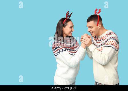 Felice giovane coppia con maglioni natalizi su sfondo blu Foto Stock