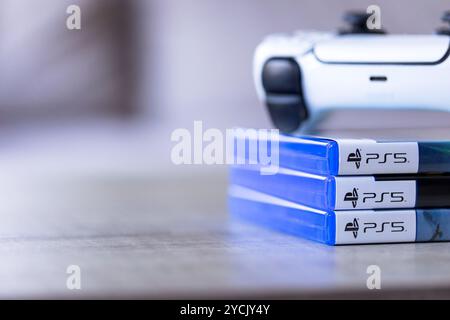 Brecht, Belgio - 3 ottobre 2024: Un controller per PlayStation 5 adagiato sopra le custodie di gioco con il logo ps5. tutto è pronto per riprodurre un video Foto Stock