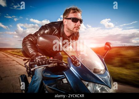 Biker in casco e giacca di pelle racing su strada Foto Stock