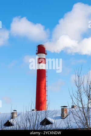 Rosso camino in fabbrica contro il cielo blu in inverno Foto Stock