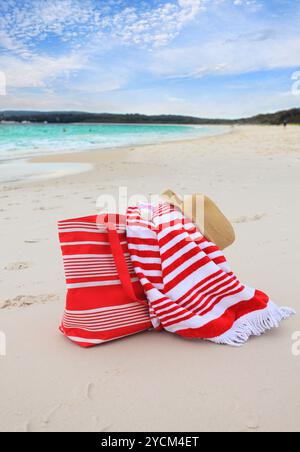 Borsa da spiaggia, telo da spiaggia, cappello e crema solare sulla spiaggia sabbiosa Foto Stock