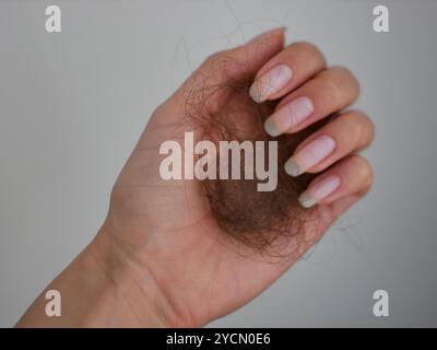 Capelli persi nella mano di una donna. Problema di caduta dei capelli dopo lo stress o la malattia ormonale. Salute delle donne di capelli, unghie e pelle. Concetto sanitario, vitamina, CA Foto Stock