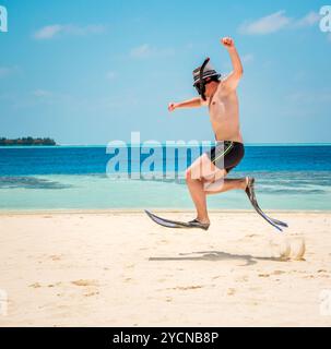 Funny Man jumping in pinne e maschera. Casa vacanze su una spiaggia tropicale a isole delle Maldive. Foto Stock