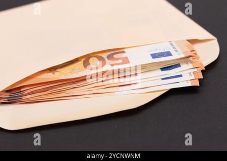 Busta di carta arancione con pila di banconote da 50 euro all'interno. Stipendio in contanti. Sistema esentasse. Valuta euro. Pagamenti senza tasse. Orange Paper Money. Un sacco di cinquanta euro Bills Foto Stock