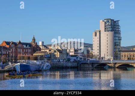 Lungo il fiume Lagan Laganside di Belfast, moderno complesso di appartamenti, Queens Bridge e Confiance Barge accanto all'area degli sport acquatici di Lagan. Foto Stock