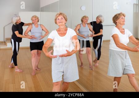 Le donne anziane che esercitano la danza balletto si muove con il formatore Foto Stock