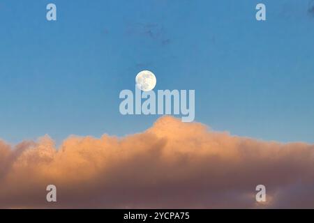 Luna quasi piena che sorge su una nuvola di tramonto a maui. Foto Stock