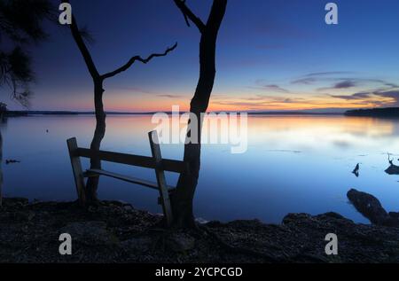 Gli ultimi colori del tramonto svaniscono all'orizzonte mentre cala la notte in questo tranquillo luogo appartato sul bacino di St Georges, vicino a Jervis Bay, Australia. Foto Stock