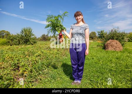 Giovane donna tenendo un covone di verdura in mano Foto Stock
