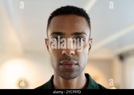 Uomo afroamericano sicuro di sé a casa che guarda direttamente la macchina fotografica, esprimendo la calma della messa a fuoco Foto Stock