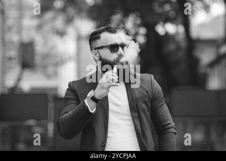 L'uomo con la barba fuma sigaretta elettronica Foto Stock