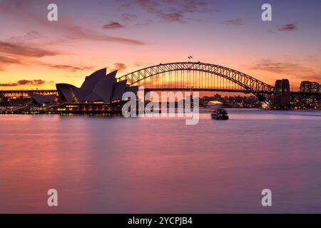 Tramonto mozzafiato sul porto di Sydney con riflessi vibranti nelle acque e viste a ovest del Sydney Harbour Bridge che si innalza su Milsons Point e. Foto Stock