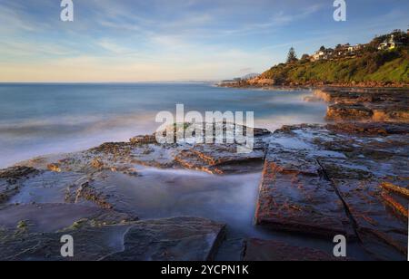 Vista a sud dalla piattaforma rocciosa di Wombarra subito dopo l'alba. Esposizione lunga. Foto Stock