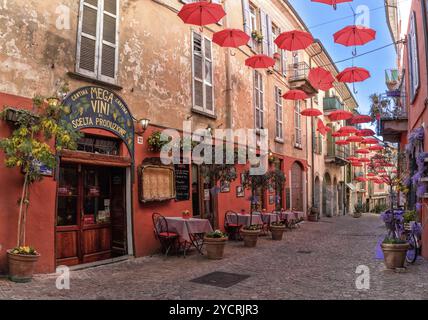 Luino, Italia, 16 marzo 2023: Strada acciottolata con piccoli negozi e decorazioni colorate nel centro storico di Luino, Europa Foto Stock