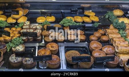 Conwy, Regno Unito, 27 agosto 2022: Vista ravvicinata di una vetrina di macelleria con una varietà di bistecche e torte di maiale, Europa Foto Stock