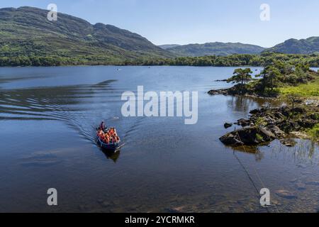Muckross, Irlanda, 10 agosto 2022: I turisti si godono un giro in barca sul lago Muckross nel Parco Nazionale di Killarney in una splendida giornata estiva, in Europa Foto Stock