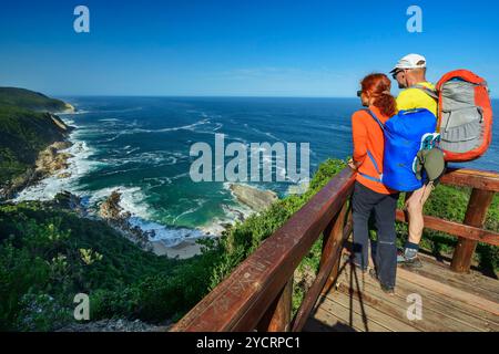 Uomo e donna che camminano in piedi sulla piattaforma panoramica e che guardano alla spiaggia sabbiosa di Blou Baai, Otter Trail, sezione Tsitsikamma, Garden Route National Park, Foto Stock
